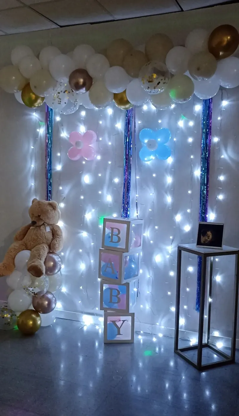 Sala decorada para baby shower con cortina de luces, globos pastel y oso gigante en Sabadell