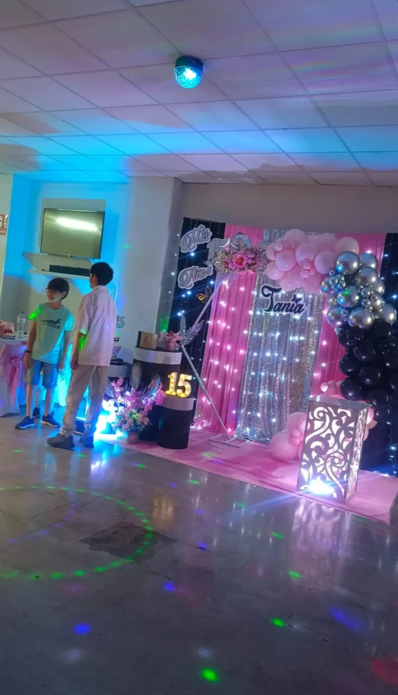 Sala decorada para quinceañera con globos rosas, dorados y fondo plateado con el nombre de la festejada en Sabadell